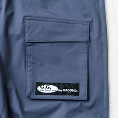 比翼フラップ付きカーゴポケット、ロゴ入りネーム（左）